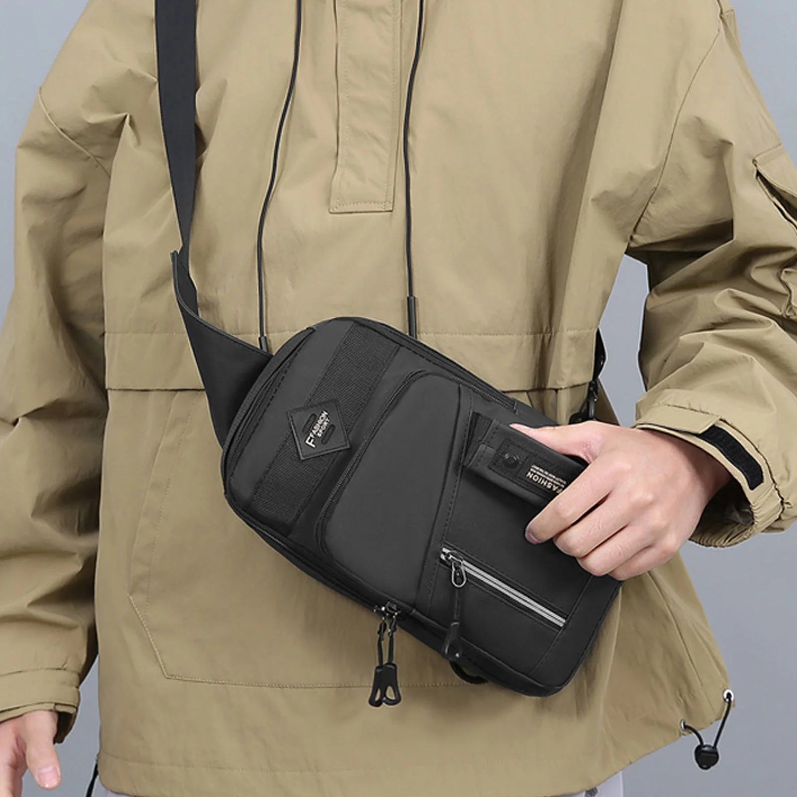 Close-up of a hand holding the handle of a black men's chest bag original product to show portability.