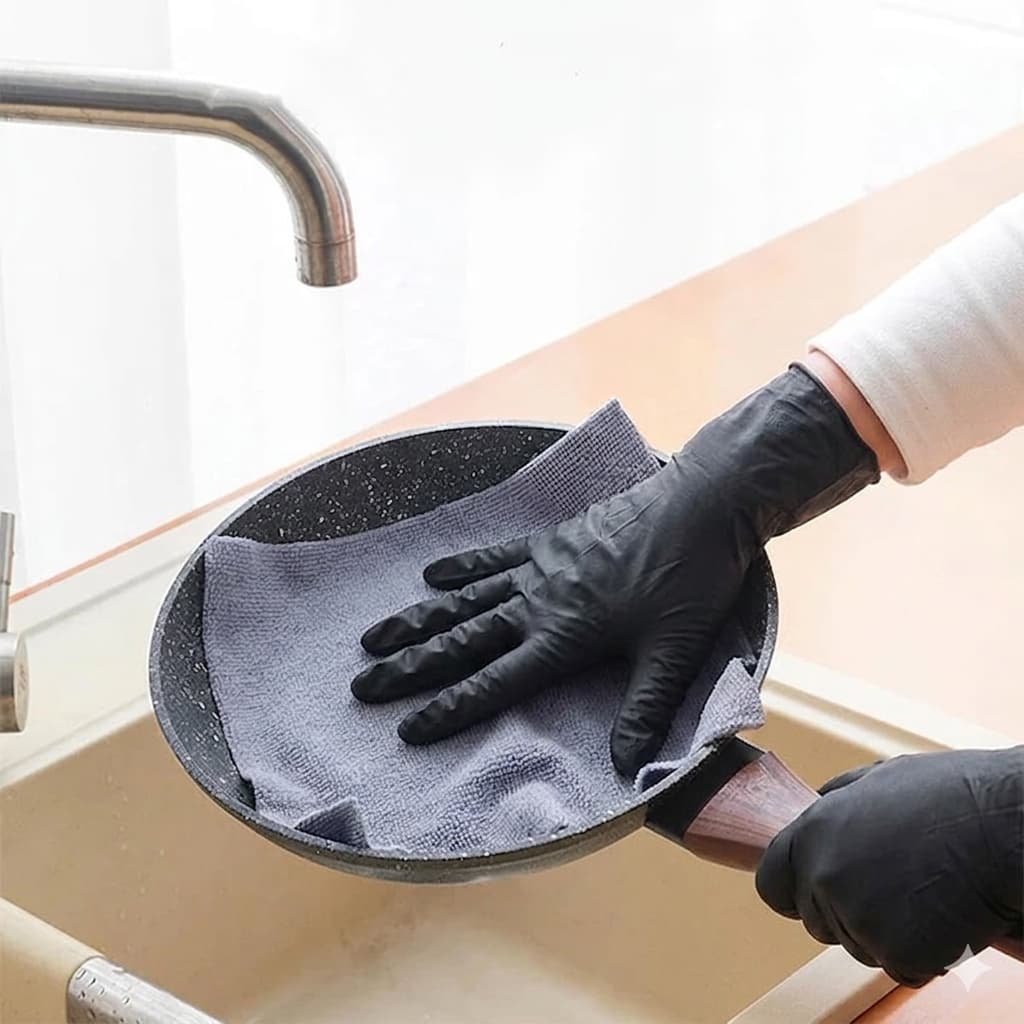 Close-up of a person using grey microfiber cleaning wipes to safely clean a non-stick pan without scratching.