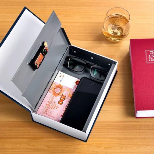 Original product dictionary book locker used for storing cash, phone, and glasses on a wooden desk.