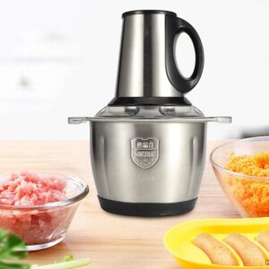 A powerful stainless steel electric meat grinder and food processor shown on a wooden kitchen table with bowls of freshly minced meat and shredded carrots.